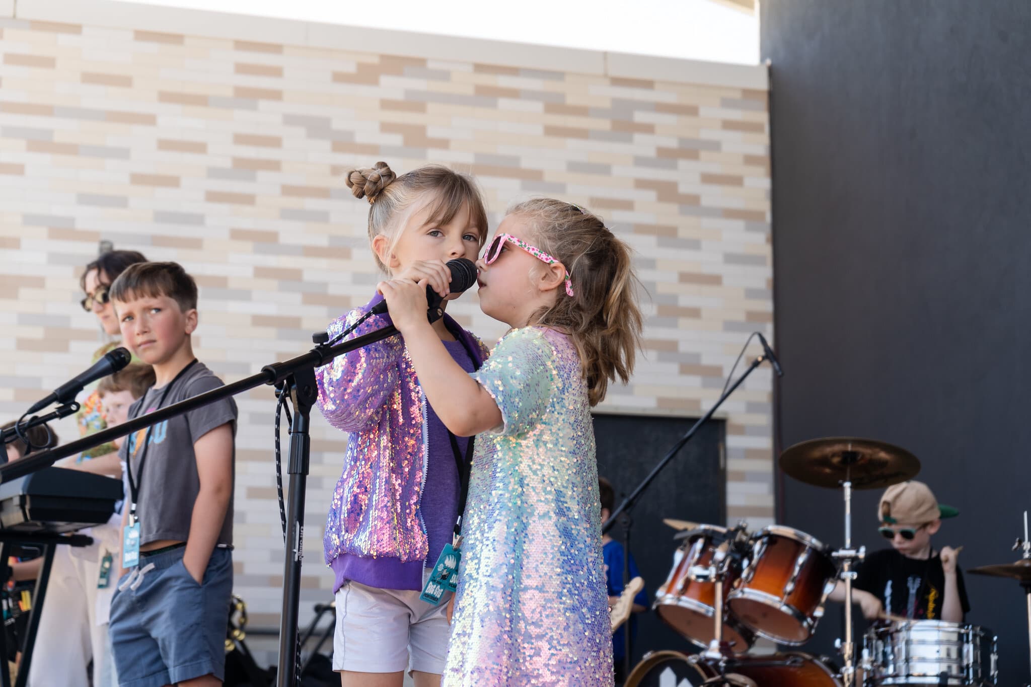 Two young singers sharing a microphone on stage